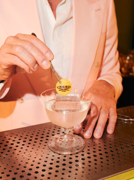 The Notorious Cocktail of Philoxenia Events placing a bespoke lemon coin garnish with the House of Creed logo on an Aventus-inspired cocktail