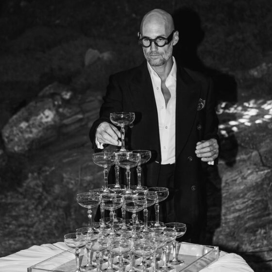 Giorgio Tosato from Philoxenia Events placing the last glass on a champagne tower during a luxury wedding in Corfu